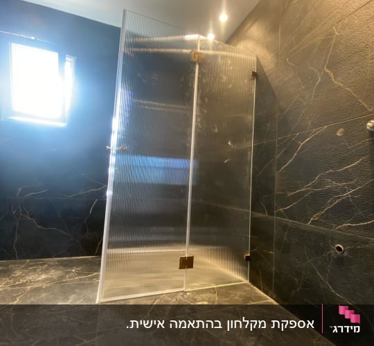 התקנת מקלחון זכוכית מחורצת עם צירים מוזהבים בחדר רחצה